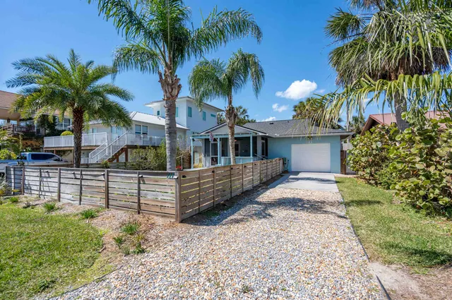 front view of house with a yard and palm trees