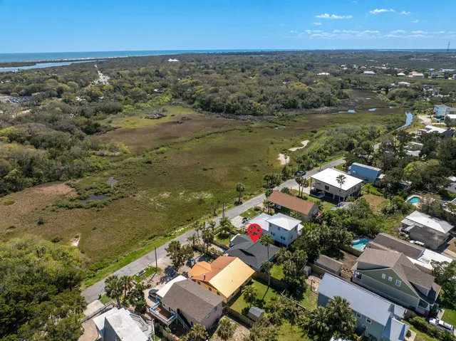 an aerial view of ocean and residential houses with outdoor space