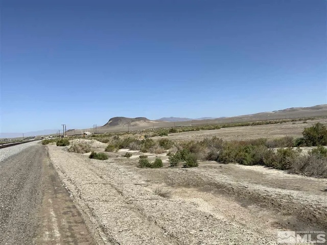 a view of a dry yard with mountains in the background