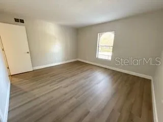 an empty room with wooden floor and windows
