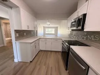 a kitchen with a sink a stove top oven and wooden floor