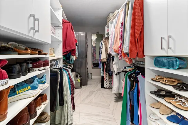a view of walk in closet with clothes and shoes