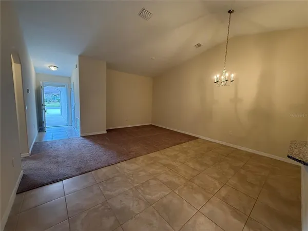 a view of a room with a hanging light and kitchen view