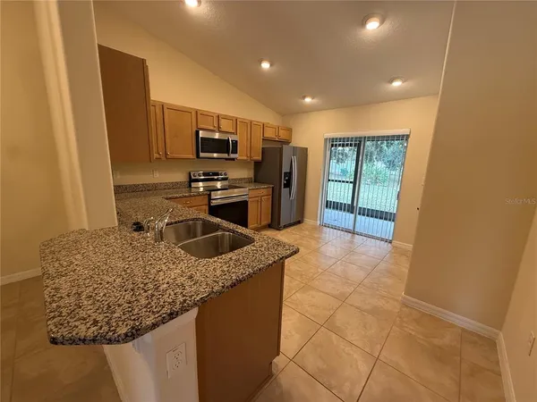 a kitchen with stainless steel appliances granite countertop a sink a stove and a refrigerator