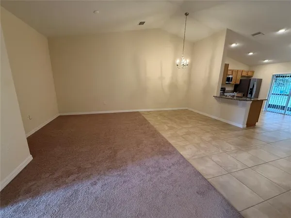 an empty room with kitchen view and a window