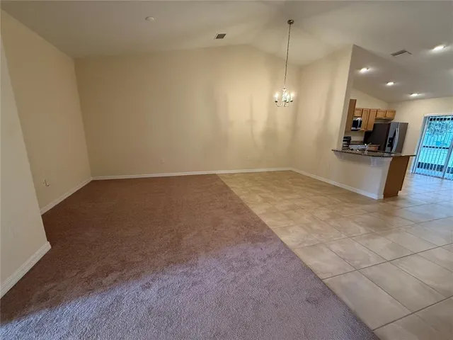 an empty room with kitchen view and a window
