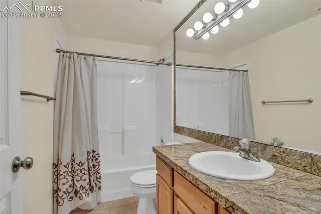 a bathroom with a granite countertop sink a toilet and shower