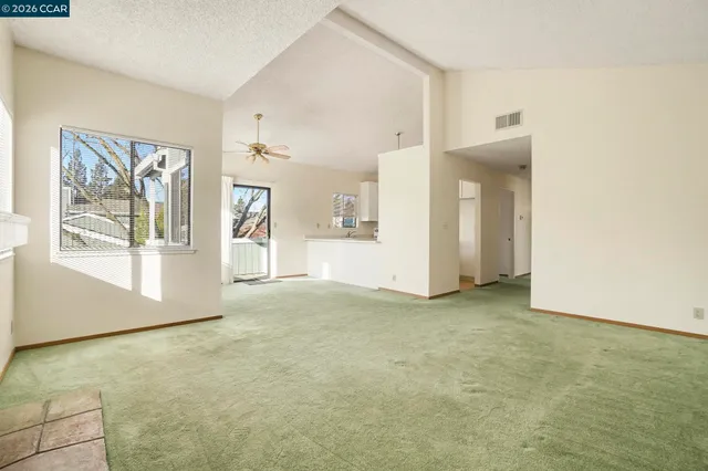 an empty room with windows and refrigerator