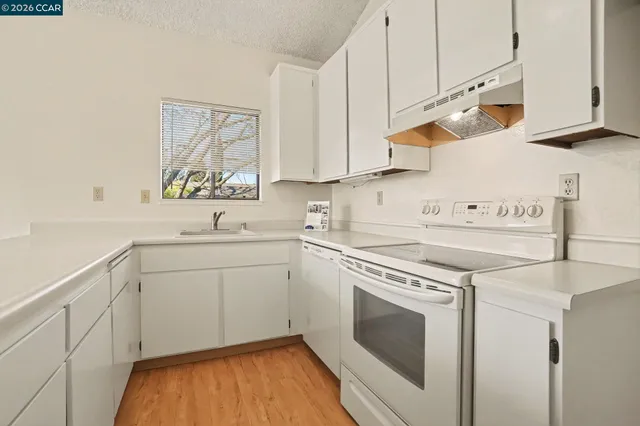 a kitchen with granite countertop white cabinets and white appliances