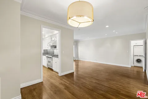 an empty room with wooden floor mirror and windows