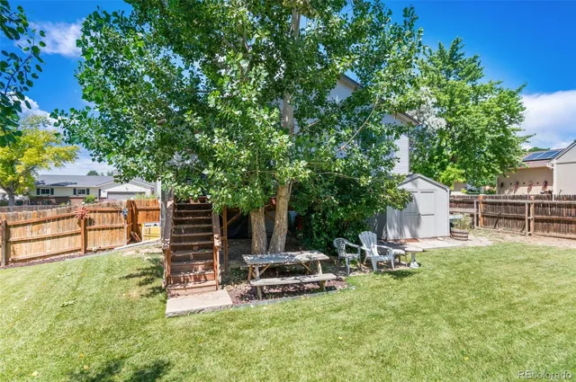 a view of a backyard with wooden fence and large trees