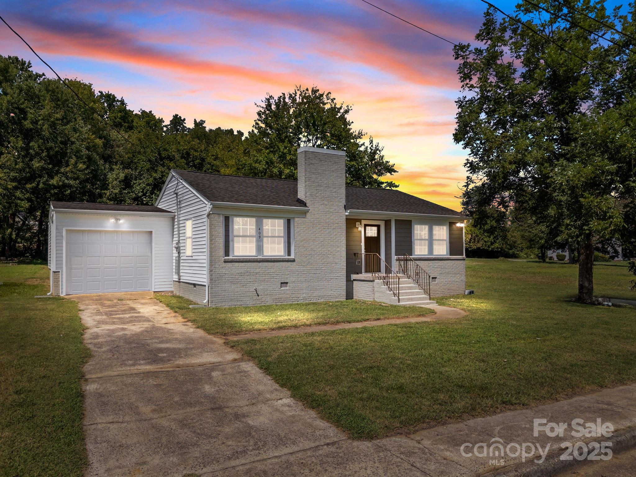 a view of a house with a big yard and large tree