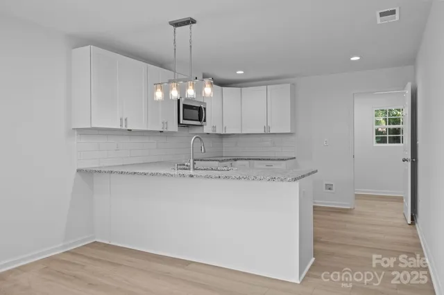 a kitchen with kitchen island granite countertop a sink cabinets and stainless steel appliances