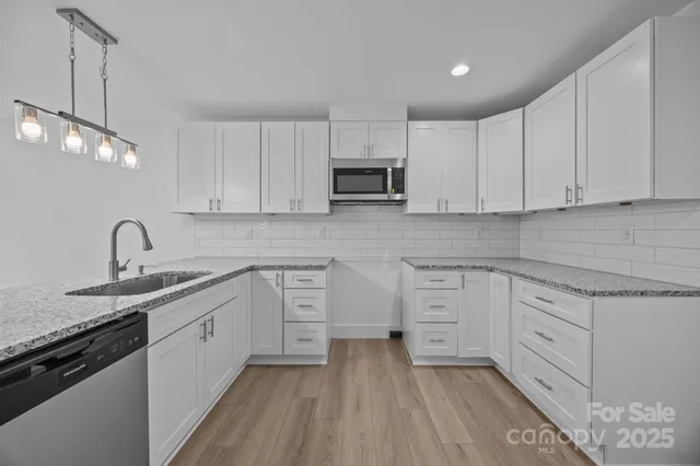 a kitchen with stainless steel appliances granite countertop a sink stove and white cabinets