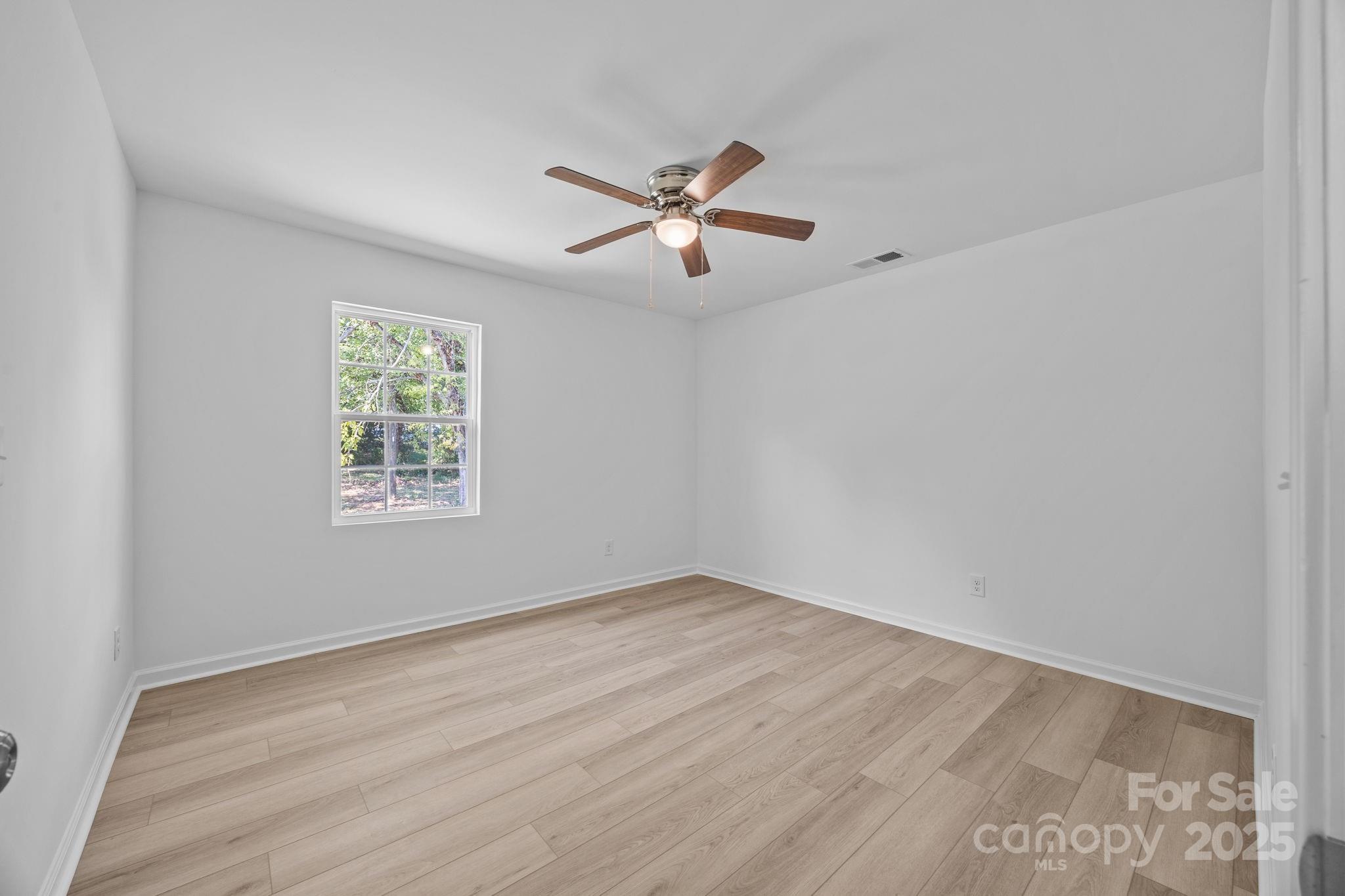 409 Shaver Street Salisbury, NC 28144 - Photo 22 of 39 an empty room with wooden floor ceiling fan and windows