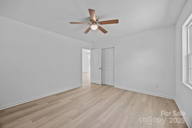 an empty room with wooden floor ceiling fan and windows