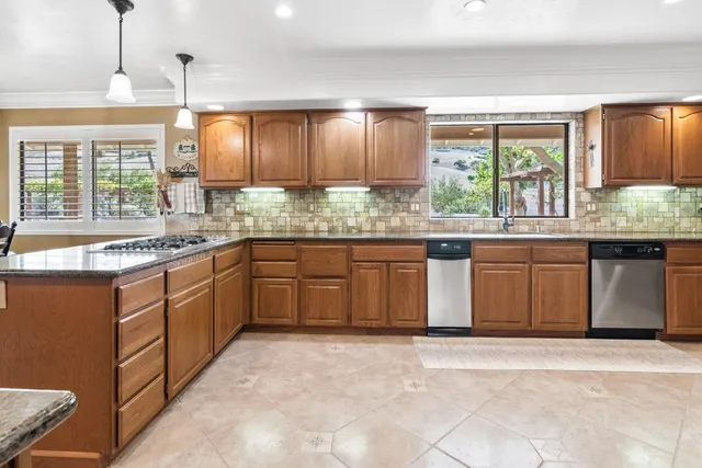 a large kitchen with stainless steel appliances kitchen island granite countertop a sink and cabinets