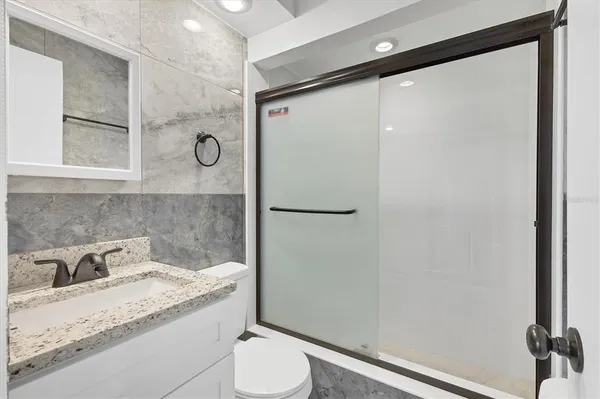 a bathroom with a granite countertop sink toilet and shower