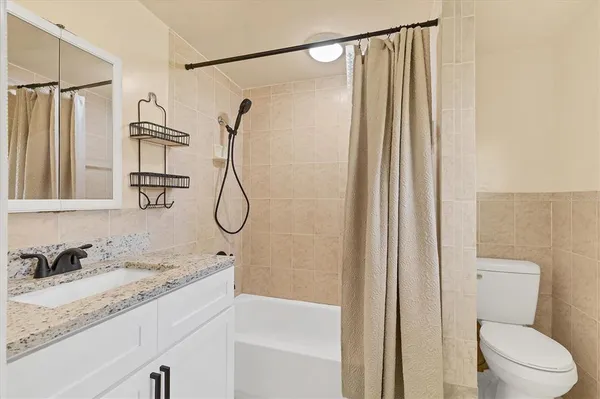a bathroom with a granite countertop sink a toilet and shower