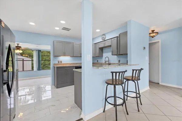 a kitchen with kitchen island a stove a refrigerator and a dining table with wooden floor