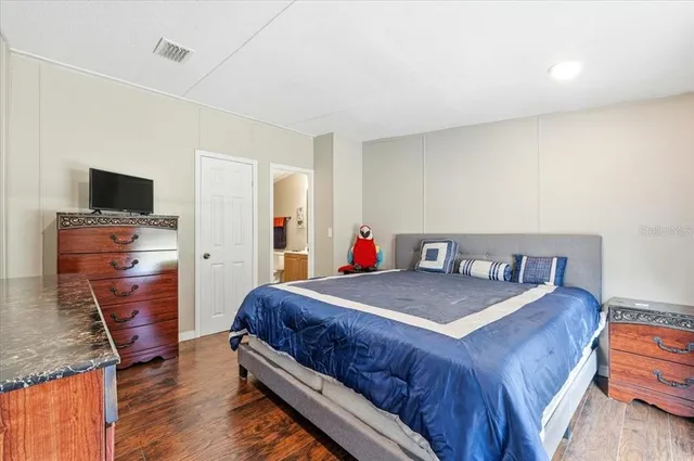 a bedroom with a bed and a flat tv screen on a dresser