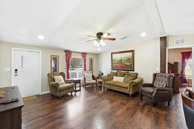 a living room with furniture kitchen view and a wooden floor