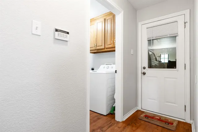 a view of a hallway with wooden floor and a bathroom