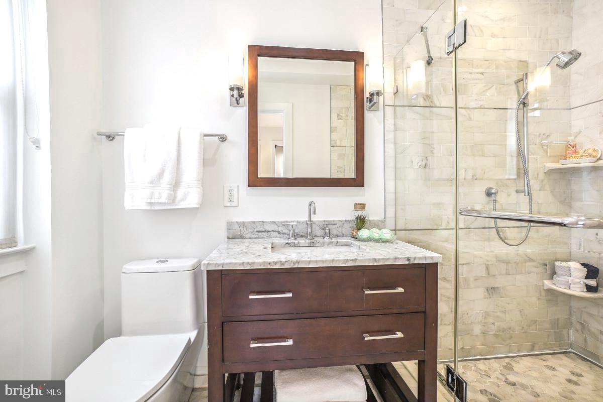 1910 Kalorama Road Northwest, Unit 403 Washington, DC 20009 - Photo 28 of 52 a bathroom with a granite countertop toilet sink and mirror