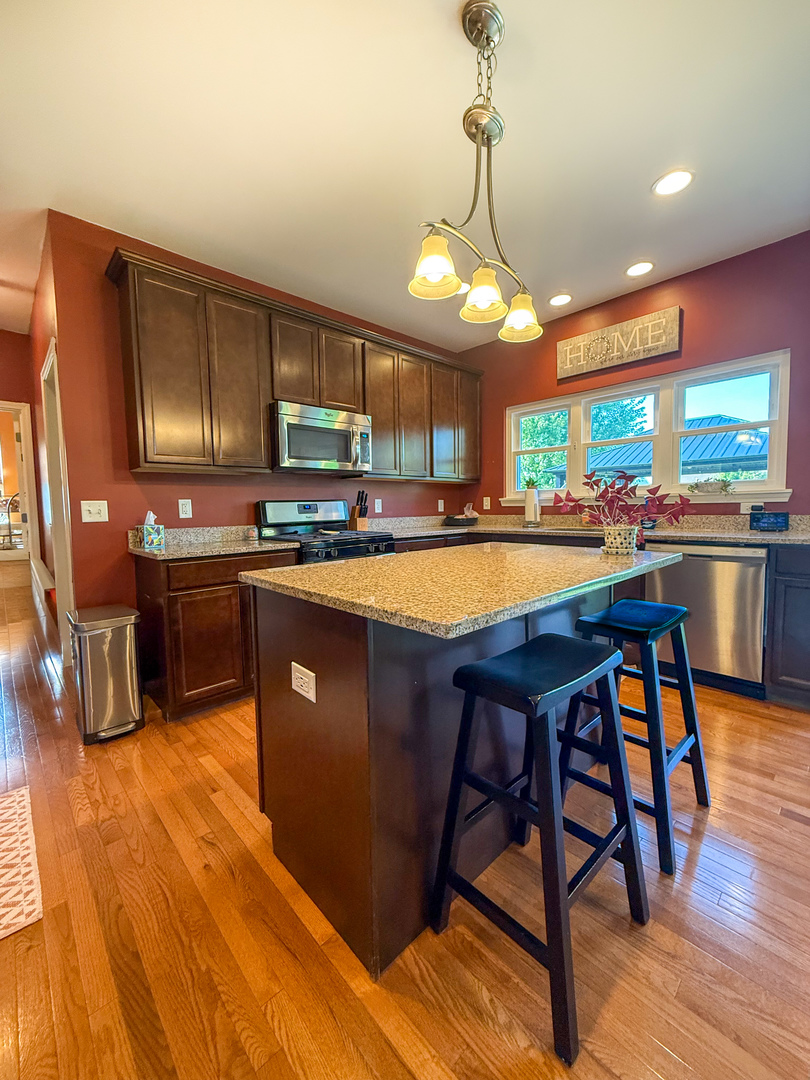 445 East Becker Place Sycamore, IL 60178 - Photo 6 of 27 a kitchen with stainless steel appliances granite countertop wooden cabinets a sink dishwasher a dining table and chairs with wooden floor