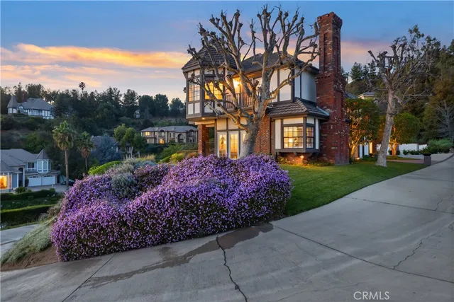 a front view of a house with a garden and trees