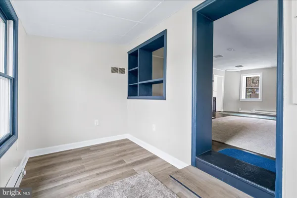 a view of empty room with wooden floor and fan