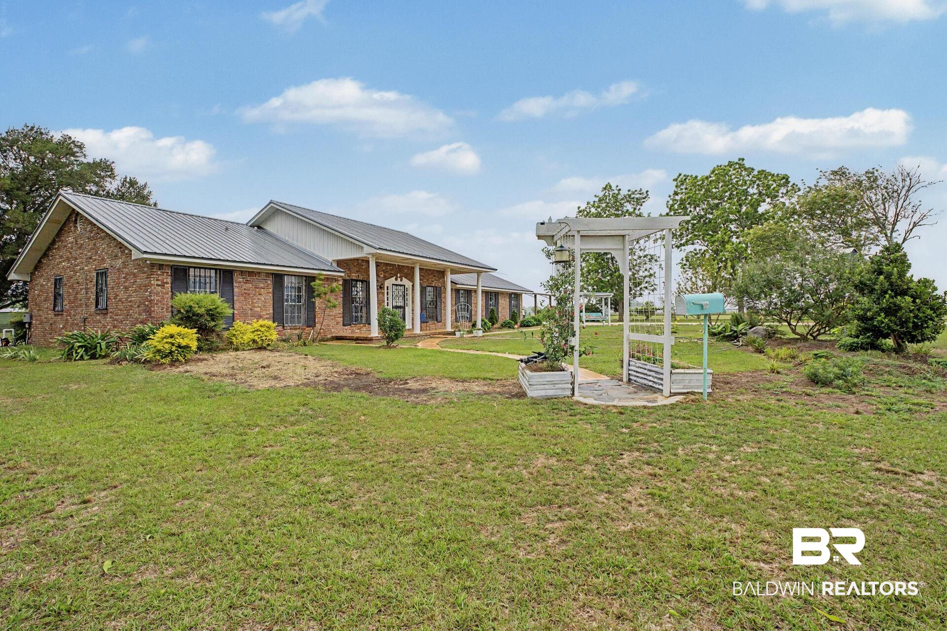 3791 Robinsonville Road Atmore, AL 36502 - Photo 9 of 47 Brick exterior residence featuring a metal roof and a covered front porch with white columns