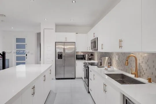 a kitchen with white cabinets a sink and stainless steel appliances