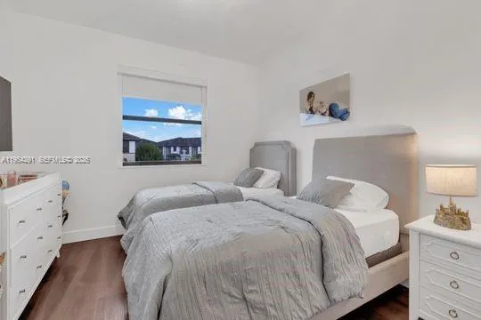 a bedroom with two beds and painting on the dresser