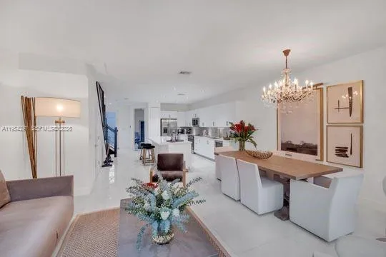 a dining room with furniture a chandelier and kitchen view