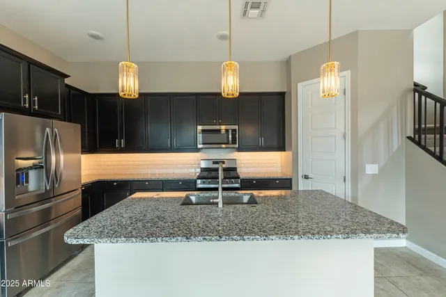 a kitchen with stainless steel appliances granite countertop a sink refrigerator and microwave