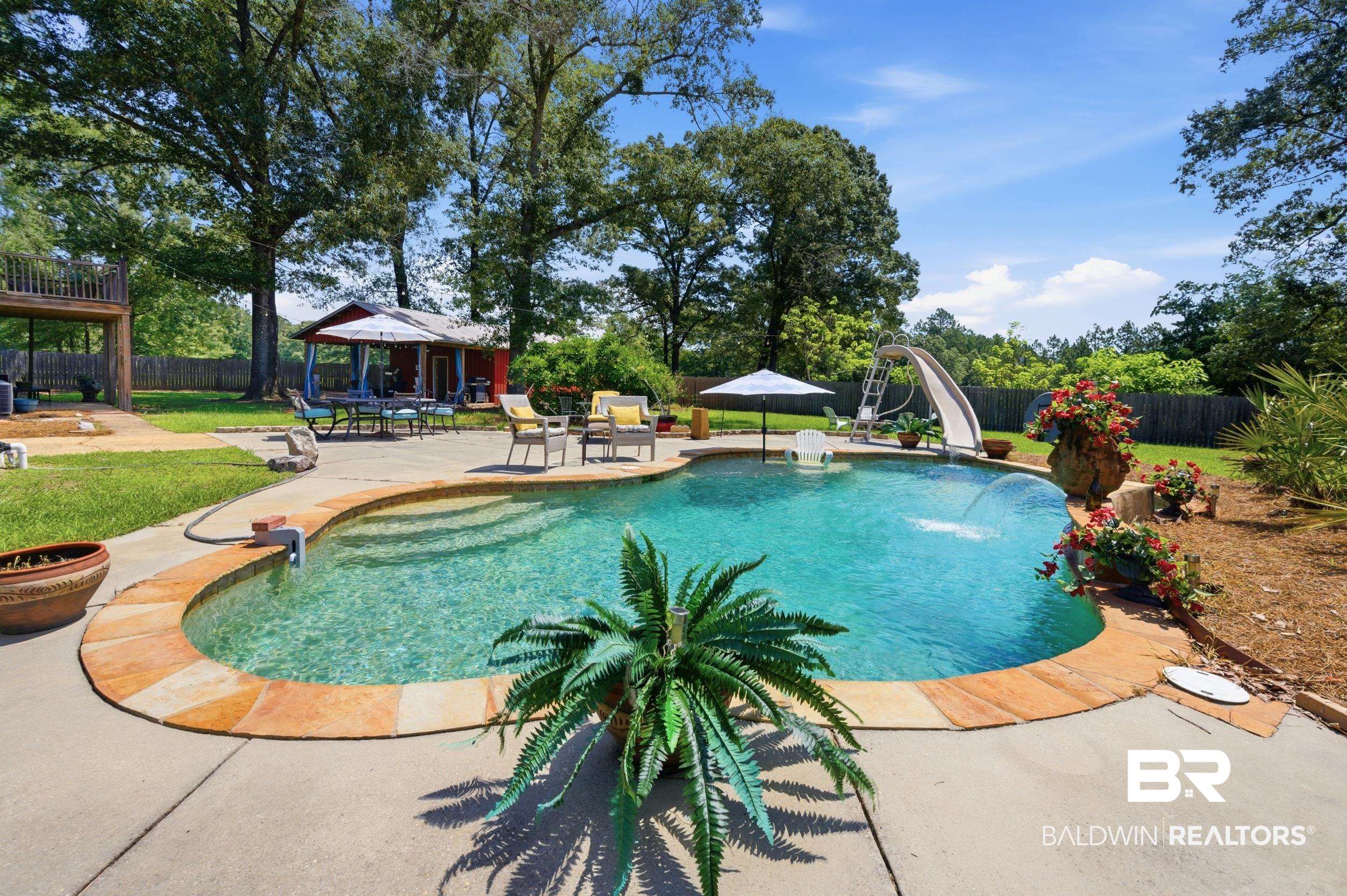 51620 Robert White Road Bay Minette, AL 36507 - Photo 70 of 81 Curved swimming pool with stone coping, an integrated slide, and a water feature