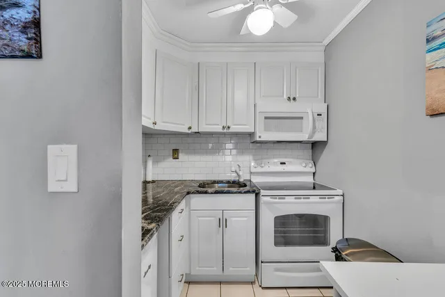 a kitchen with granite countertop white cabinets and white appliances