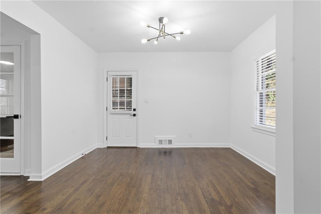 1410 Willis Mill Road Southwest Atlanta, GA 30311 - Photo 9 of 33 an empty room with wooden floor chandelier fan and windows