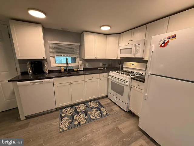 a white kitchen with sink a microwave and stove