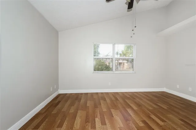 a view of empty room with wooden floor and fan