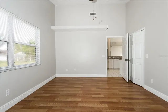 a view of an empty room with wooden floor and a window