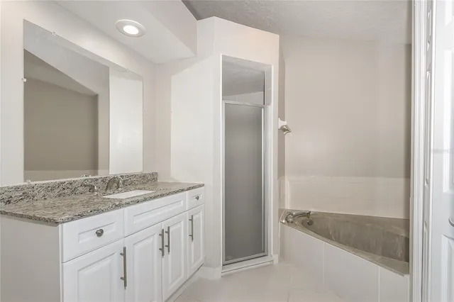 a bathroom with a granite countertop sink and mirror with bathtub