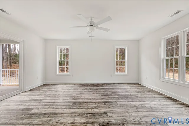 a view of an empty room with a window and wooden floor