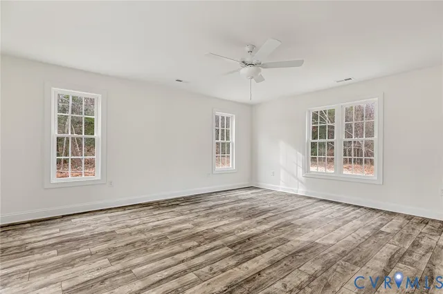 a view of an empty room with a window and wooden floor