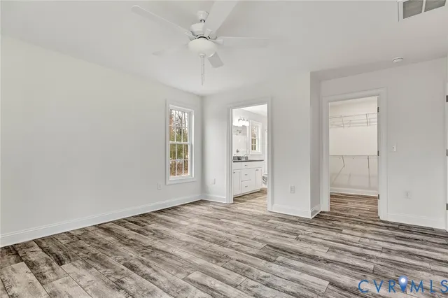 an empty room with wooden floor closet and windows