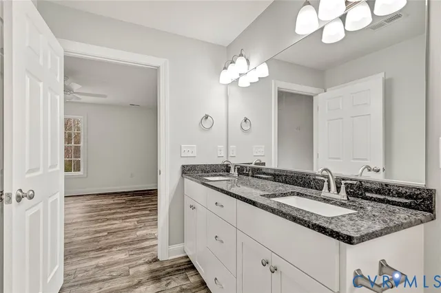 a bathroom with a granite countertop double vanity sink and a mirror
