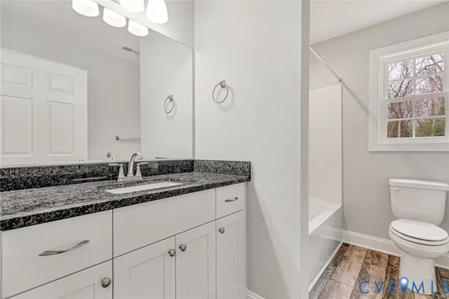 a bathroom with a granite countertop sink a toilet and a mirror