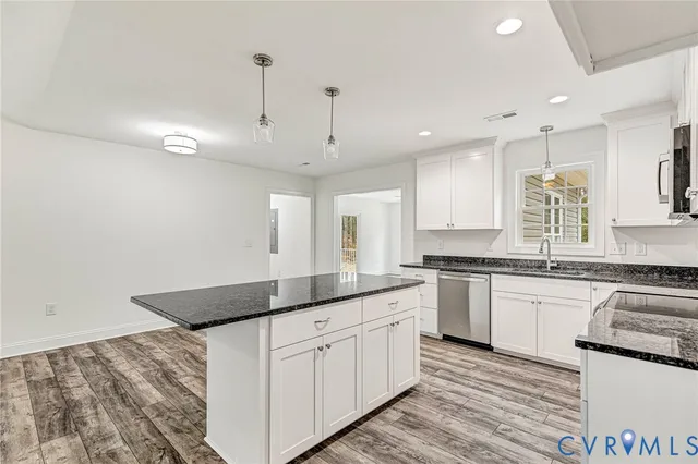 a large kitchen with granite countertop a white stove top oven and white cabinets