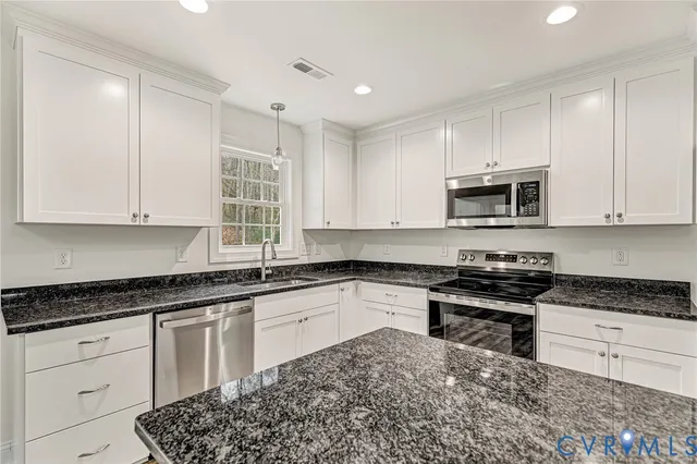 a kitchen with granite countertop white cabinets and stainless steel appliances